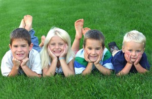 Four children on grass smiling